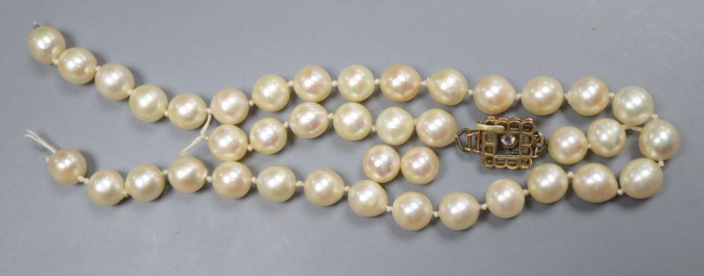 A single strand cultured pearl necklace, with yellow metal and thirteen stone diamond set clasp (strand a.f.).